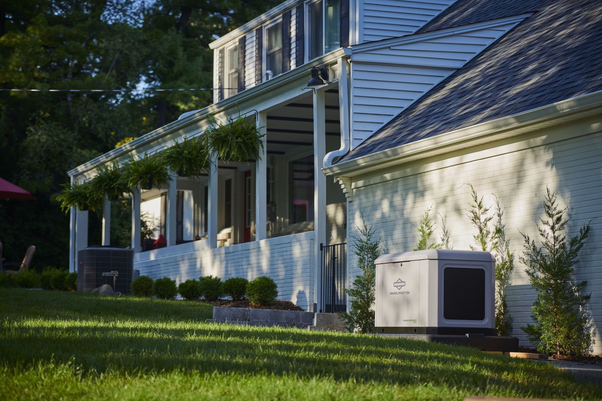 White house with blue siding, front porch, and lawn, with an outdoor air conditioner unit beside it