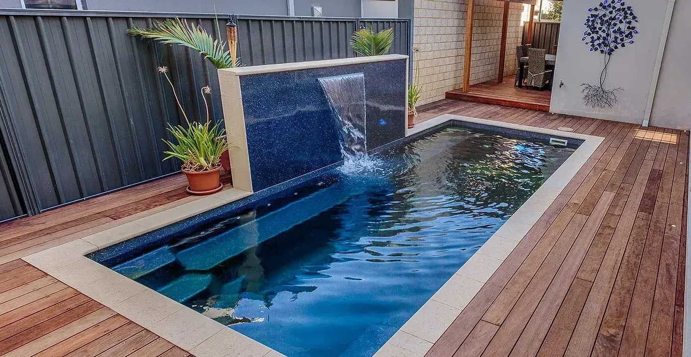 Small rectangular plunge pool with waterfall feature and wooden decking.