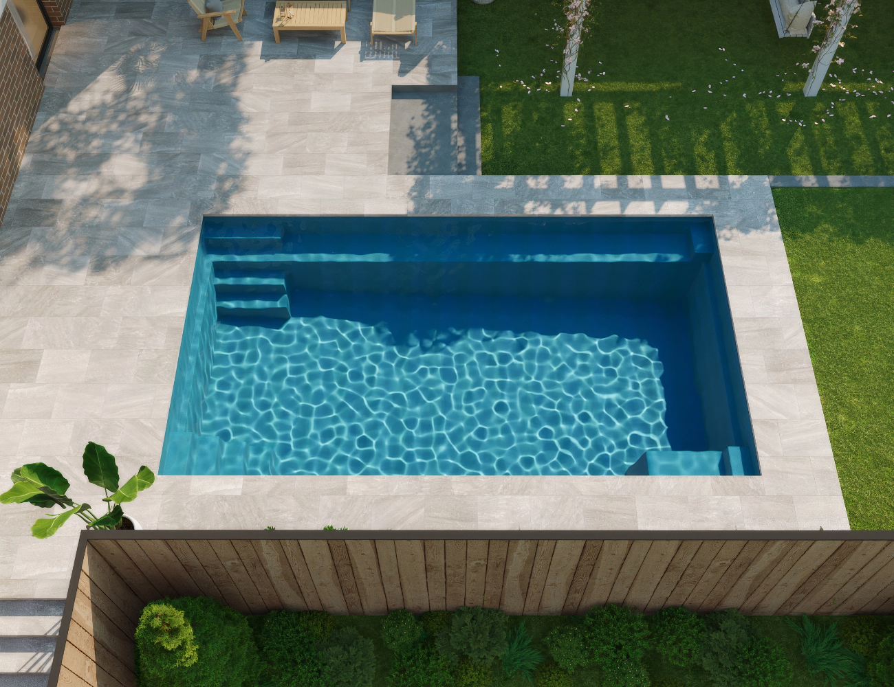 Overhead view of a rectangular pool with blue water, surrounded by light gray stone patio and green lawn.