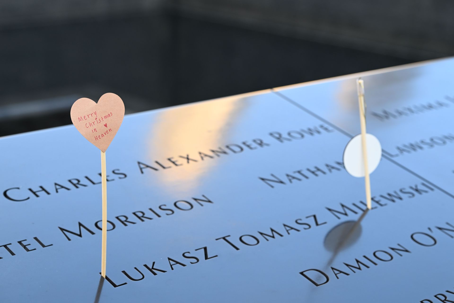 Heart-shaped pins marking names on a blue memorial plaque