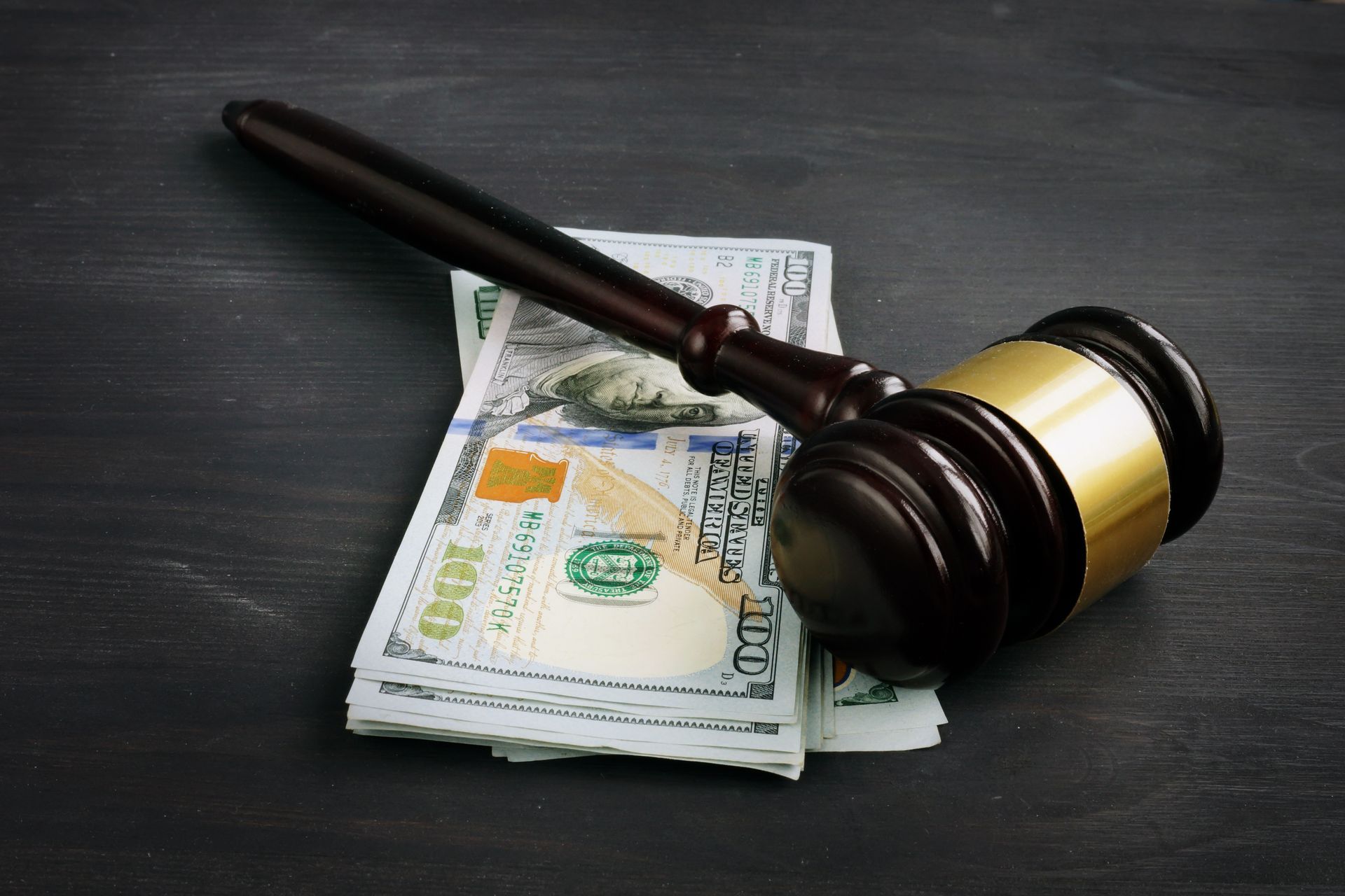 Wooden judge’s gavel resting on U.S. dollar bills on a dark table