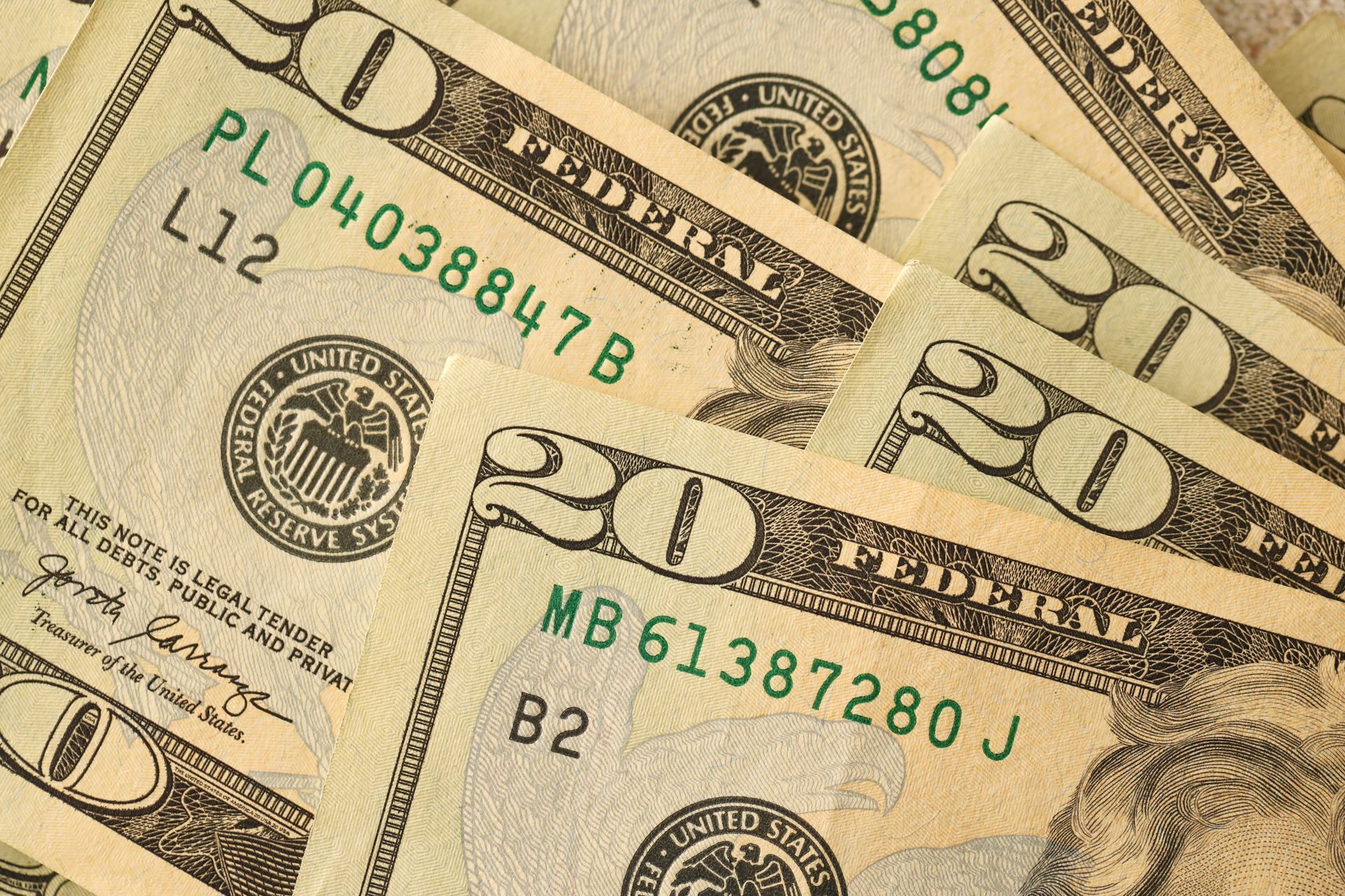 Close-up of overlapping U.S. twenty-dollar bills with green serial numbers.