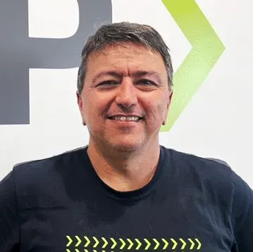 Um homem vestindo uma camiseta preta está sorrindo para a câmera.