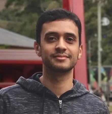 Um homem com barba está usando um moletom e olhando para a câmera.