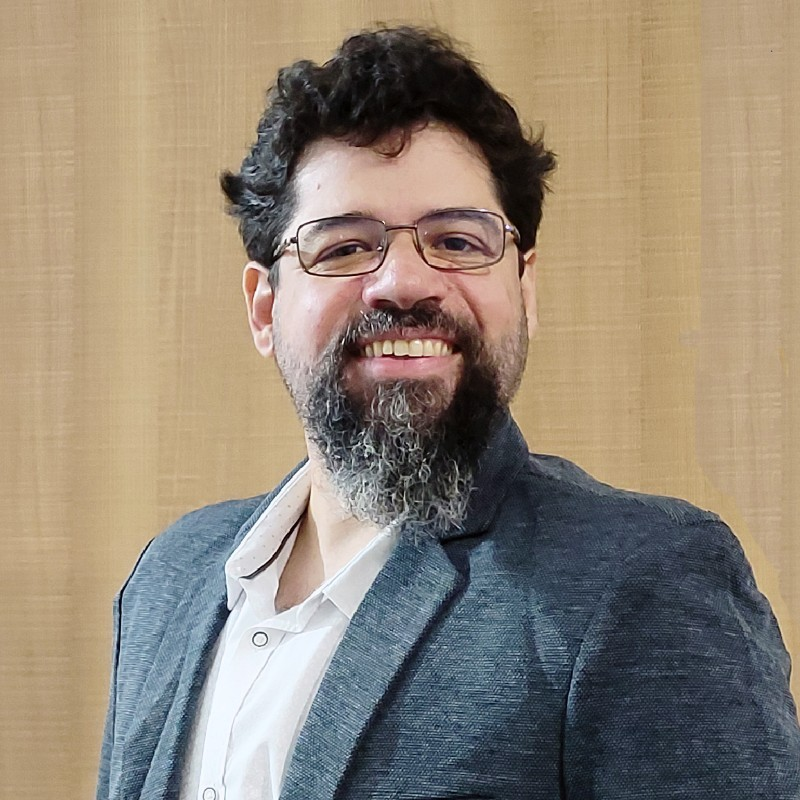 Um homem com barba e óculos está sorrindo para a câmera.