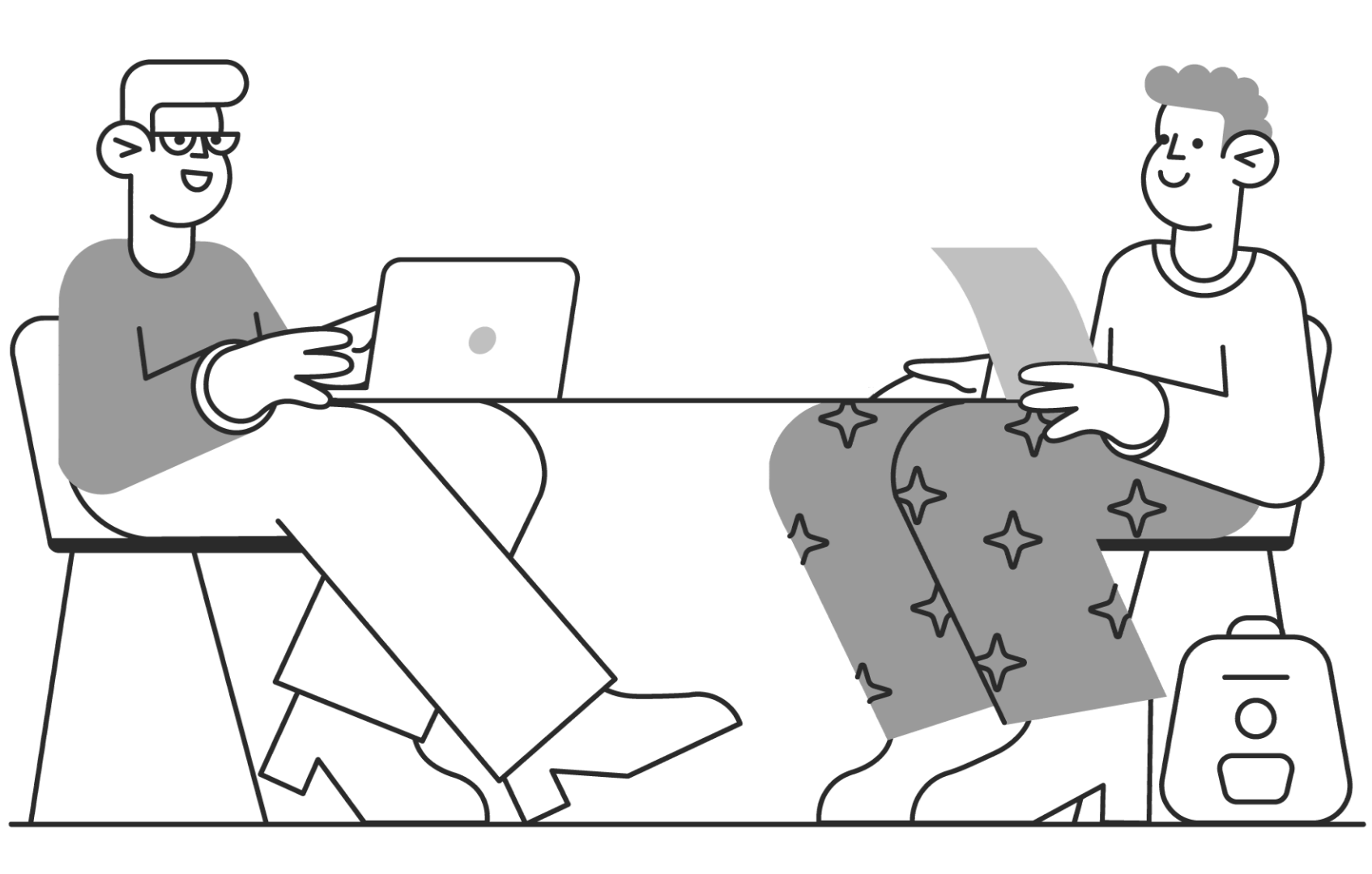 Dois homens estão sentados a uma mesa com laptops.