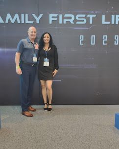 Two people posing onstage in front of a “Family First” 2023 backdrop