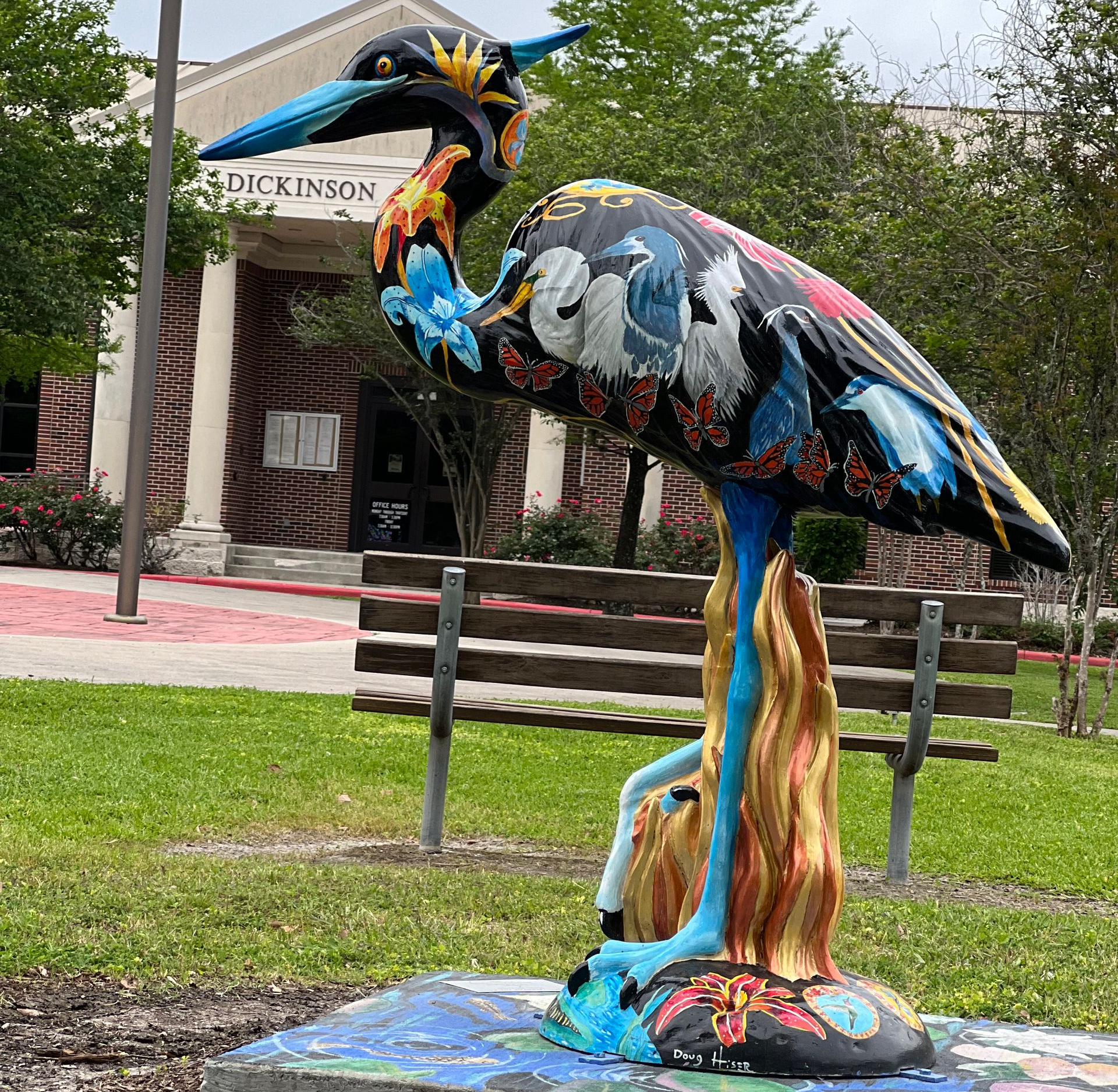Colorful bird sculpture on a campus lawn in front of a Dickinson building