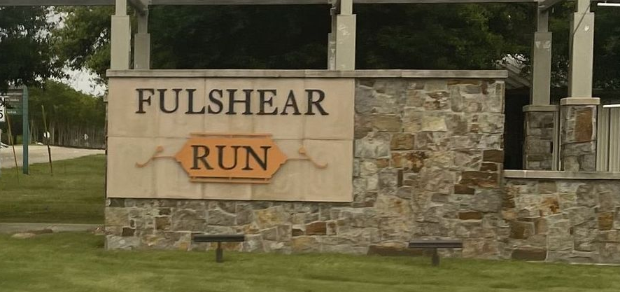 Stone entrance sign reading “Fulshear Run” in a grassy park setting
