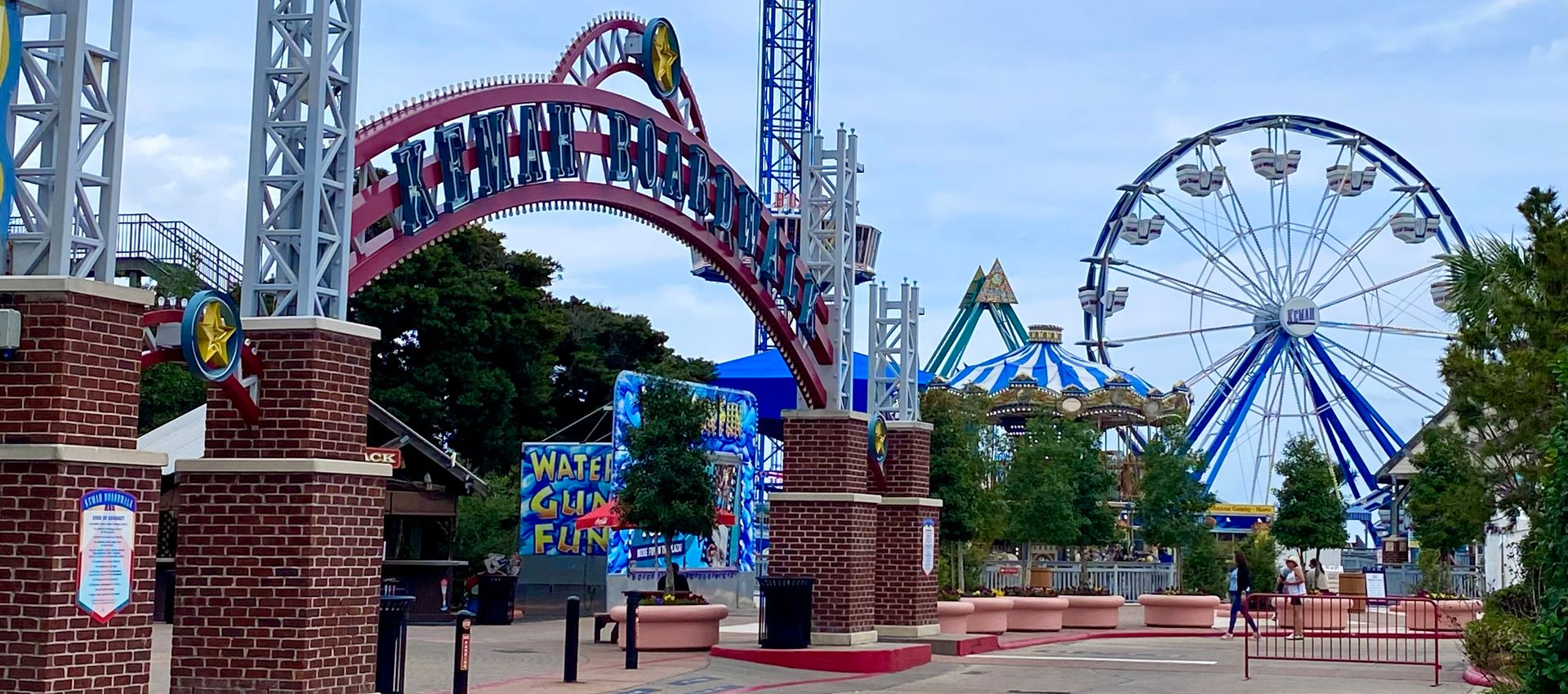 Entrance to an amusement park with colorful archway and ferris wheel in the background