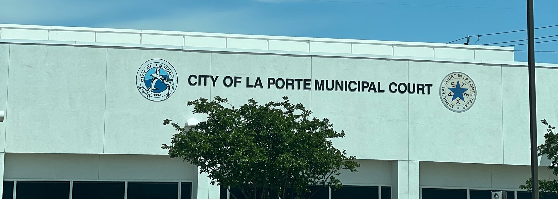 City of La Porte Municipal Court building sign on a light-colored facade with trees in front