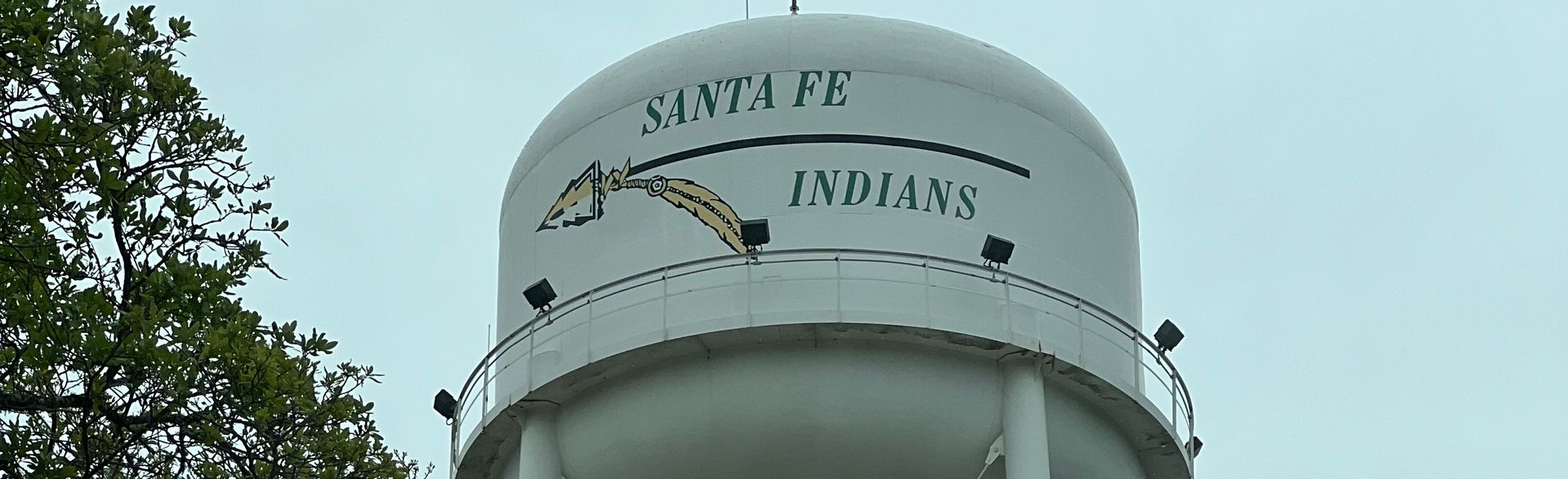 White water tower with “SANTA FE” text against a cloudy sky.