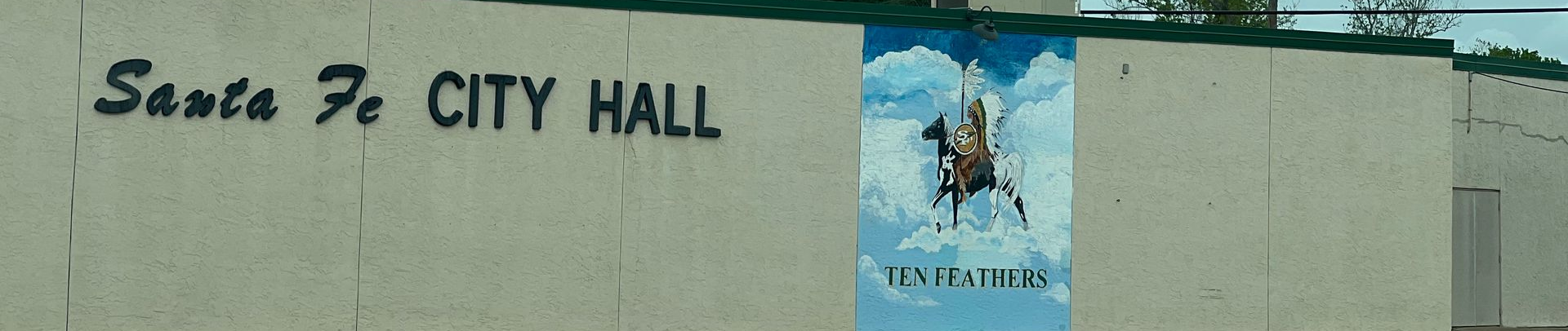 Santa Fe City Hall building sign on a beige wall with a blue mural panel
