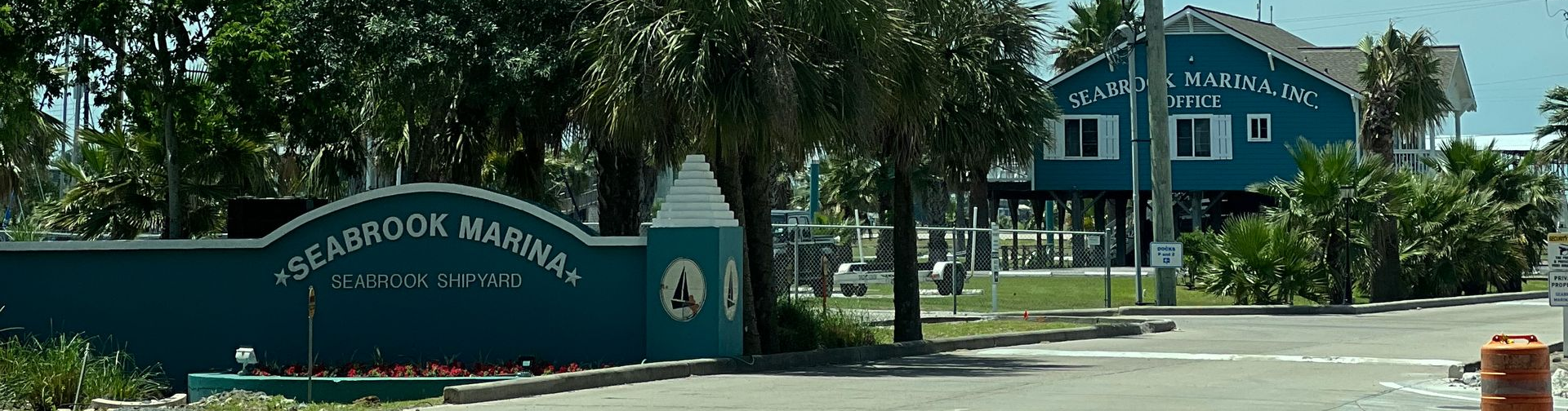 Entrance sign for a blue building amid trees and landscaping on a sunny street
