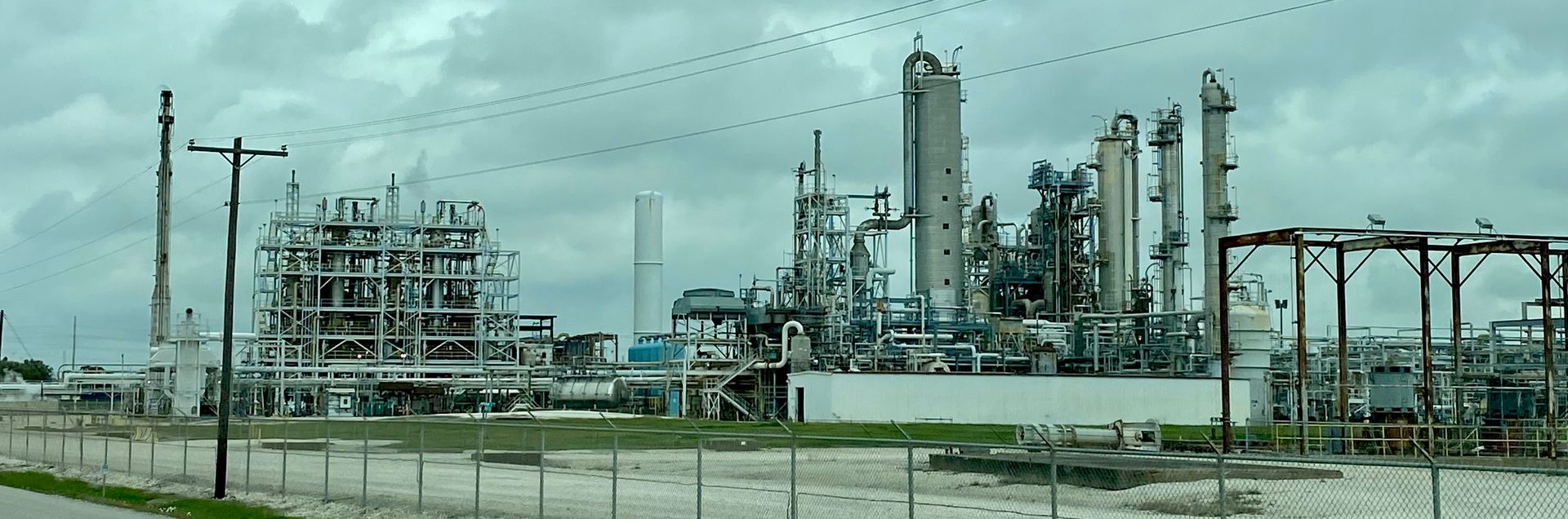 Industrial refinery with towers, pipes, and metal structures under a cloudy sky