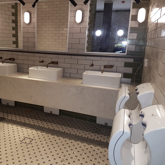 a bathroom with three sinks and two hand dryers
