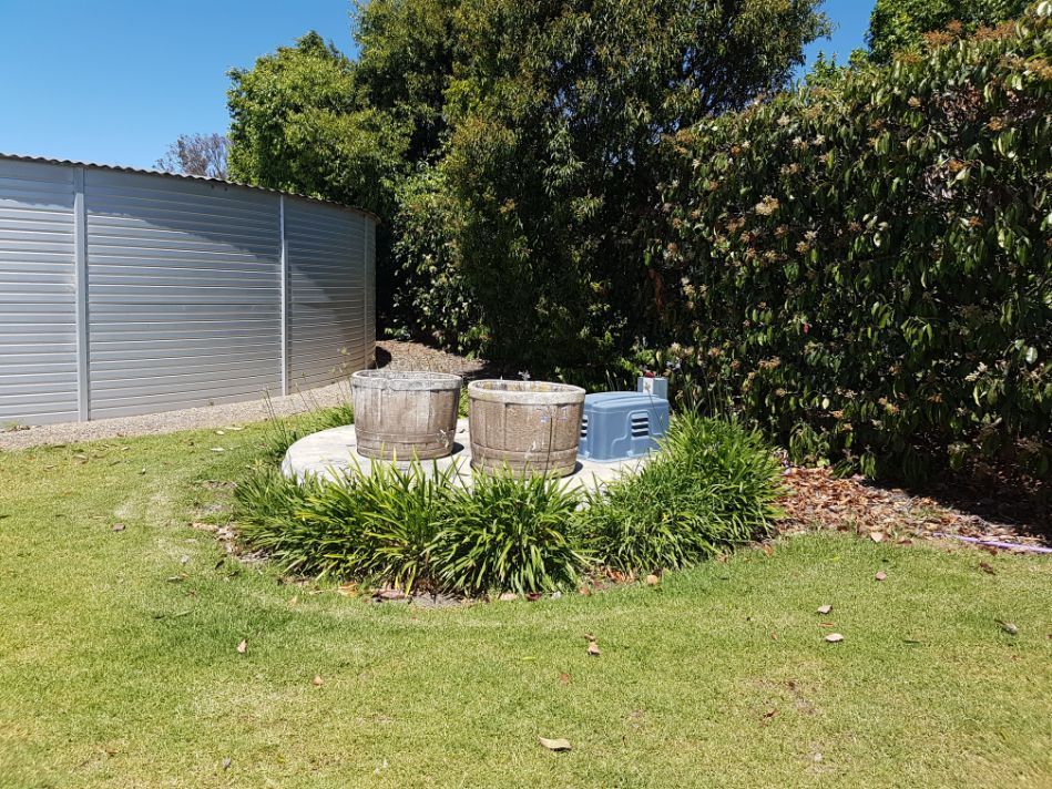 a lawn with a shed in the background and a fire pit in the middle .