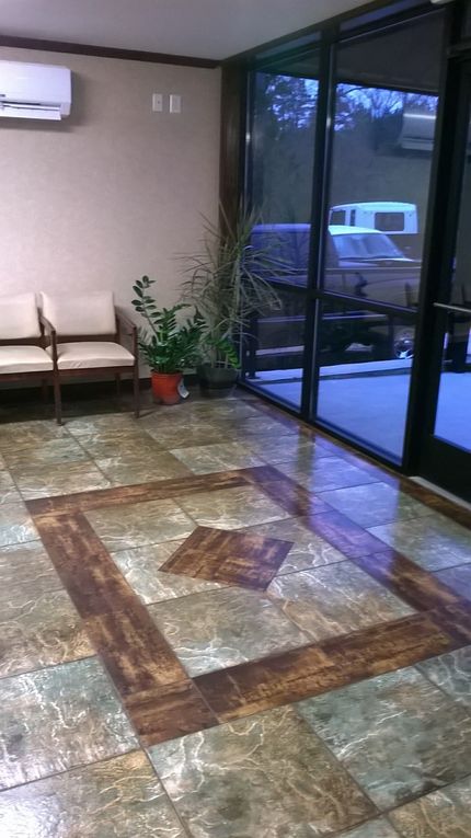 Lobby with patterned tile floor, seating, plants, and glass doors overlooking an exterior.