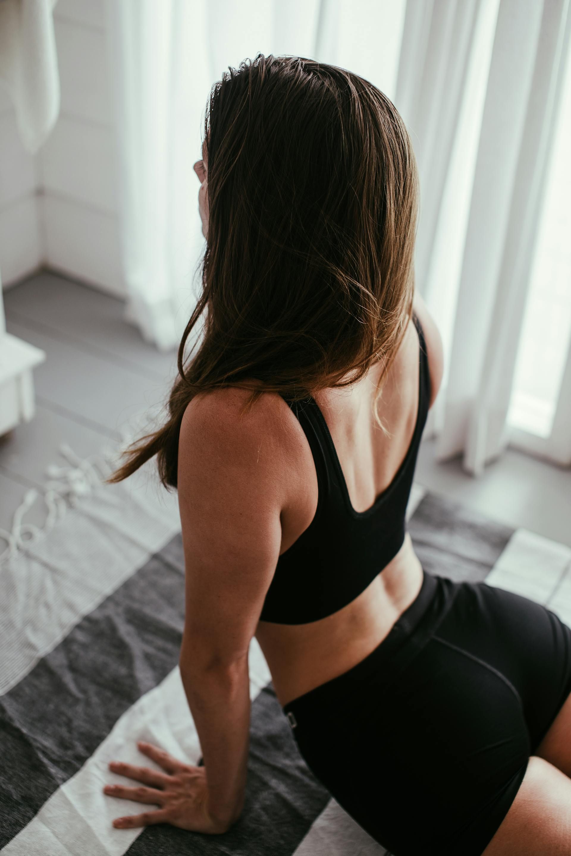 A woman in a pink sports bra is holding a pink foam roller