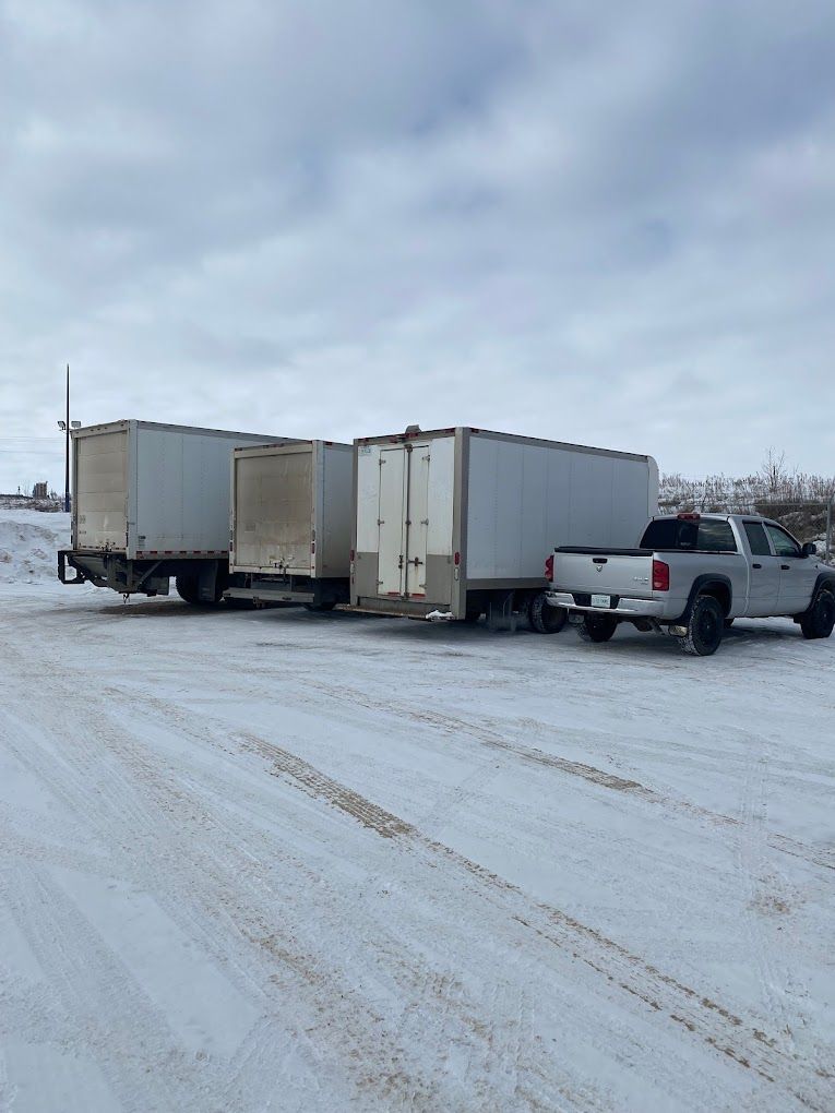 A truck and trailer are parked in a snowy parking lot.