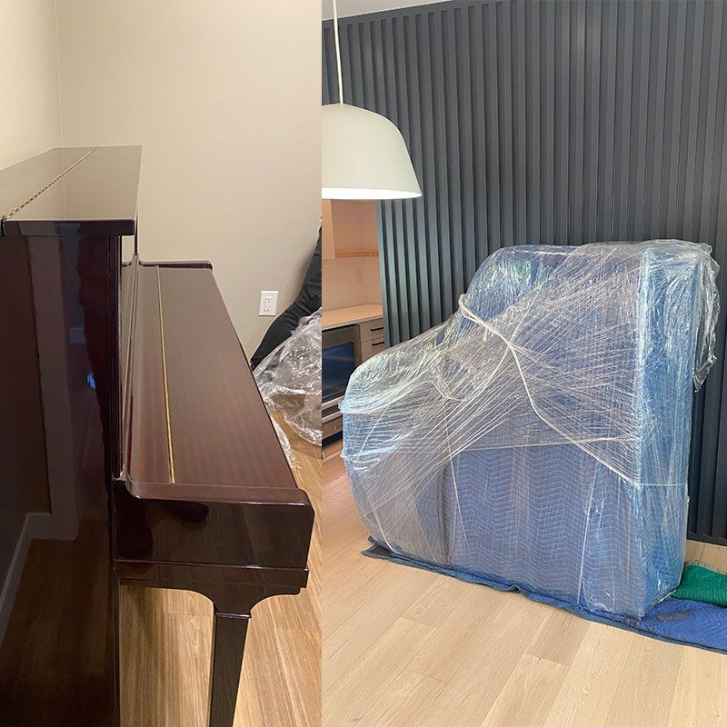 A piano is sitting in a living room next to a chair wrapped in plastic.