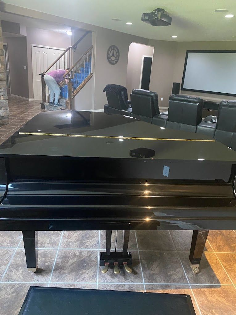 A black grand piano is sitting in a living room next to a staircase.