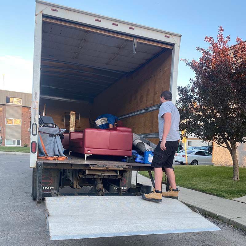 A man is standing on the back of a moving truck