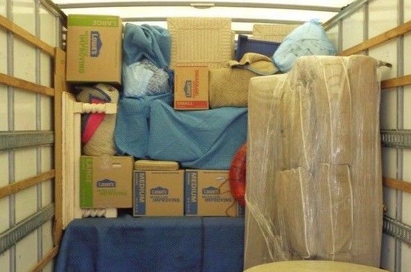 The inside of a moving truck filled with boxes and blankets