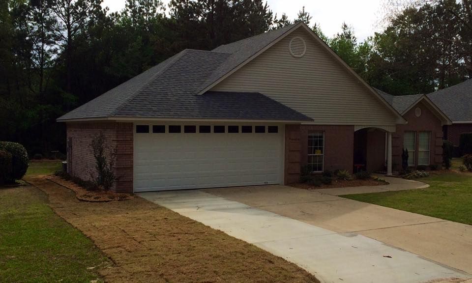 A brick house with a garage and a driveway. Overcast sky.