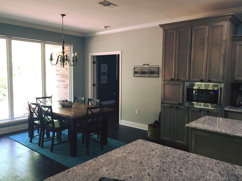 Kitchen with dining area, teal rug, dark wood table and chairs, gray cabinets, granite countertops, and a chandelier.
