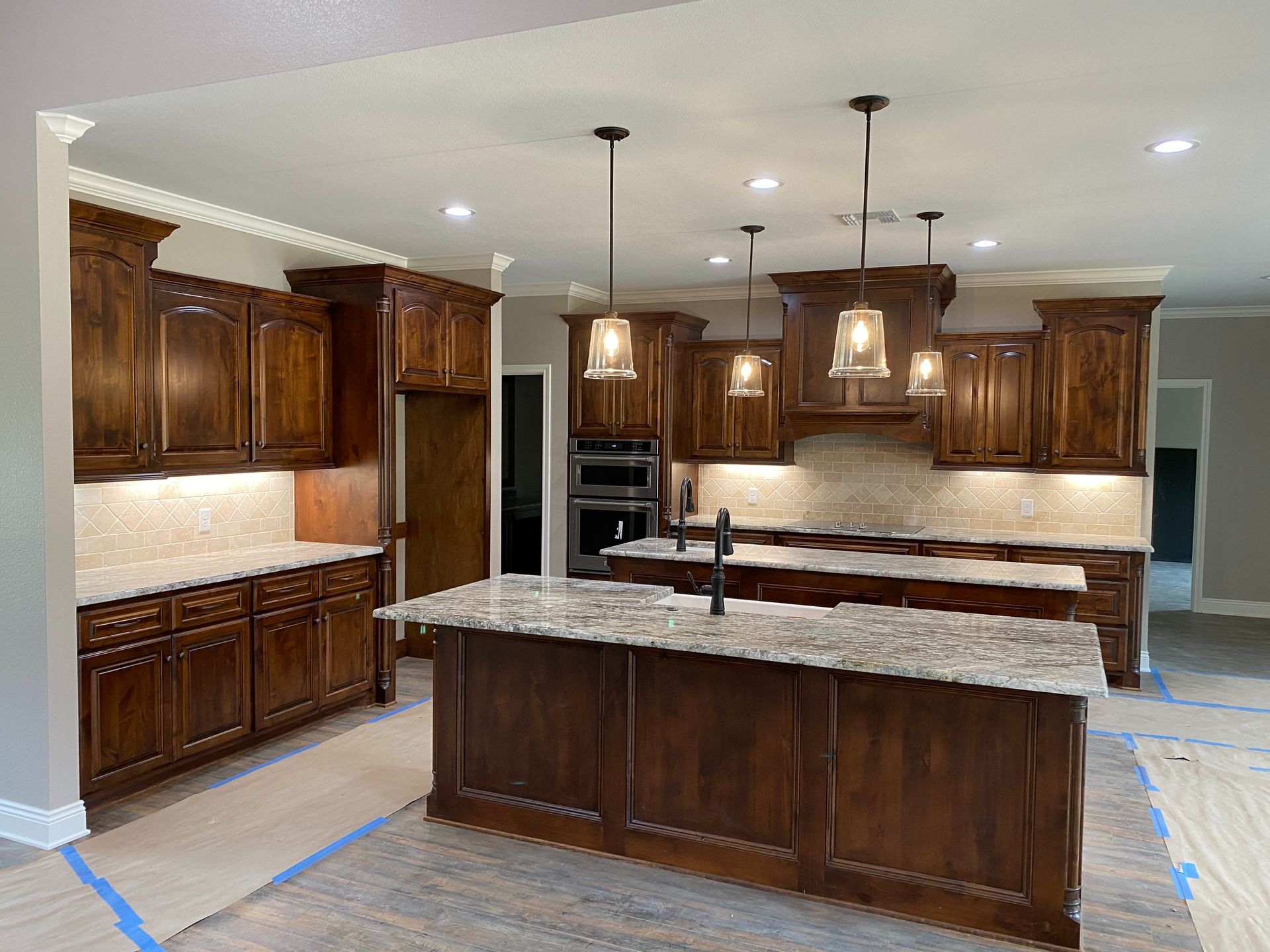 Spacious kitchen with dark wood cabinets, two islands, and pendant lights. Granite countertops.