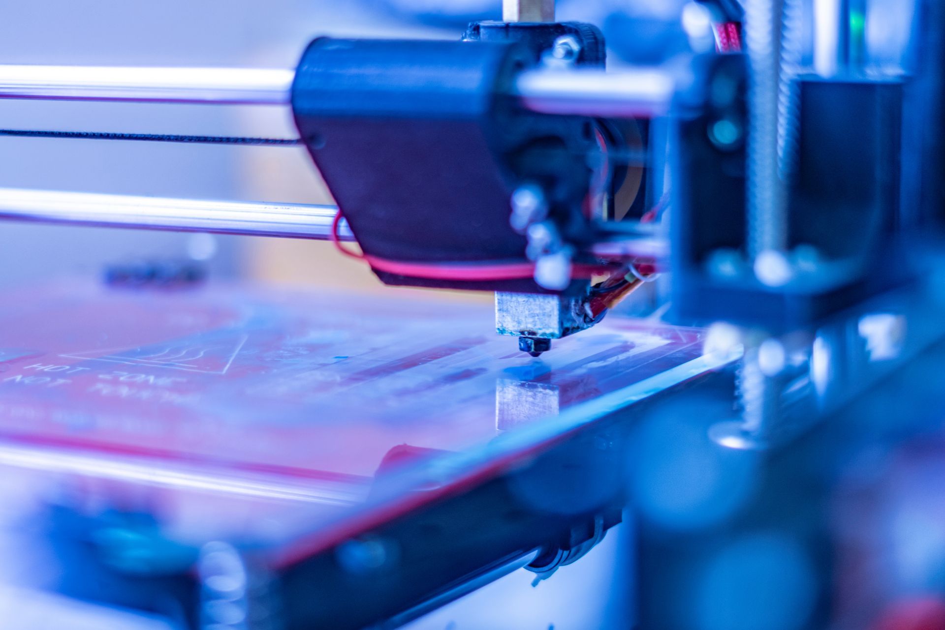 Close-up of a 3D printer nozzle layering material on a lit print bed for custom printing.