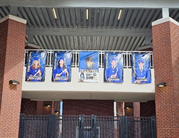 Custom school banners displaying graduating students hanging on the exterior of a school building.