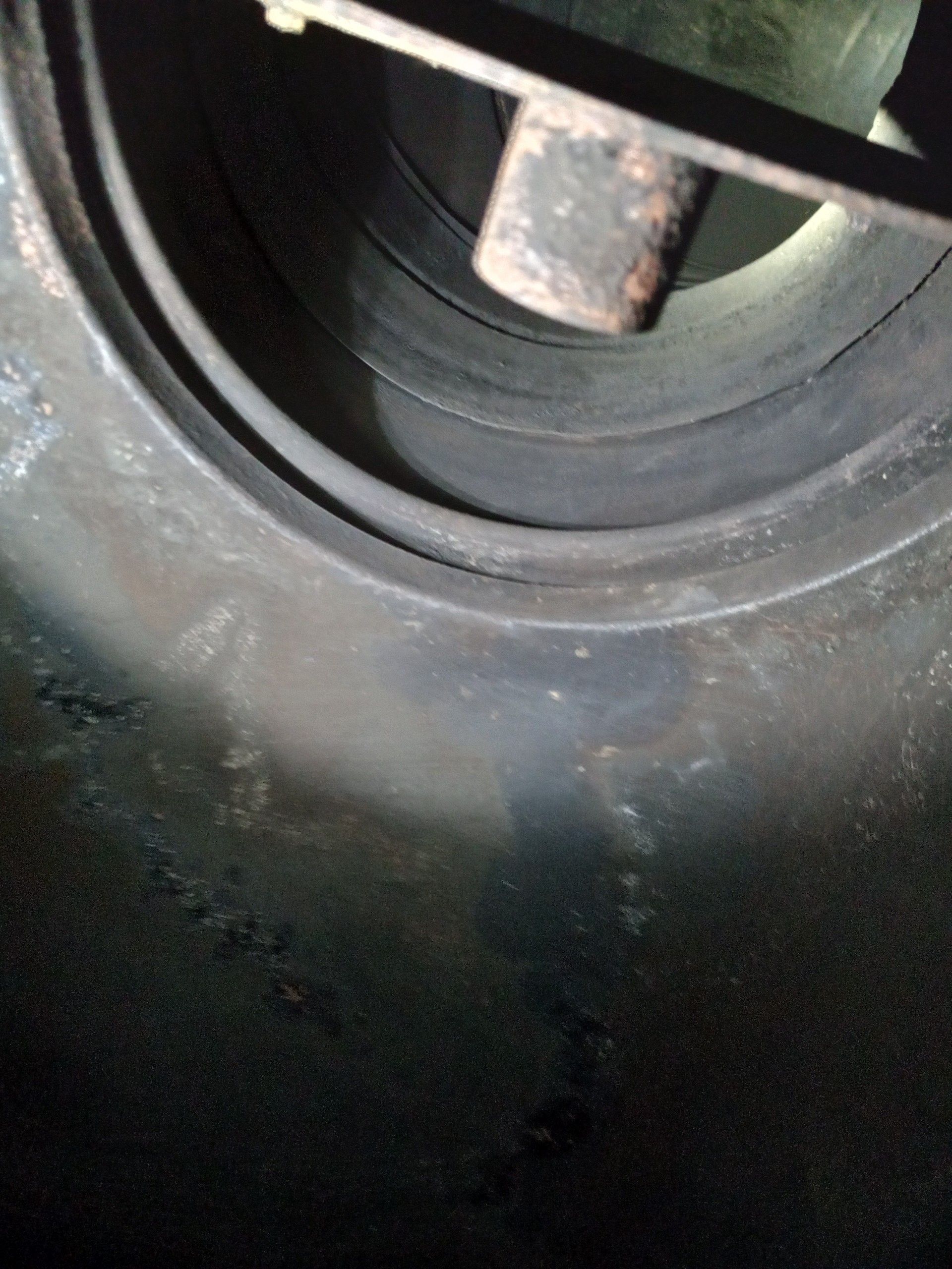 Close-up of a dark circular metal opening with a central bolt or rod inside.