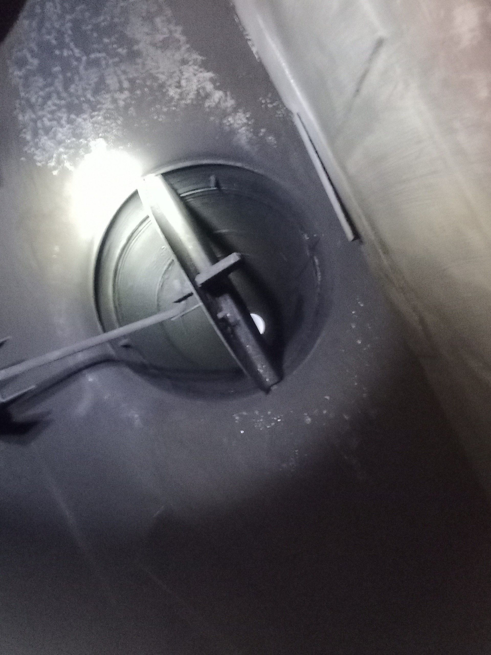 Close-up of a round gray valve or vent knob with a black crossbar on a dusty metal surface.