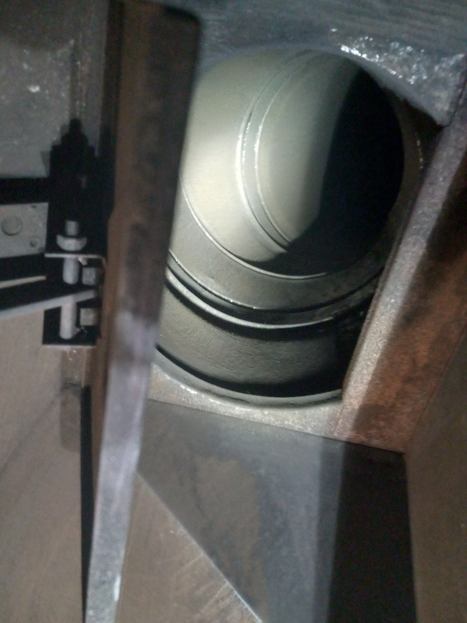Close-up of a gray cylindrical object inside a wooden cabinet or compartment.
