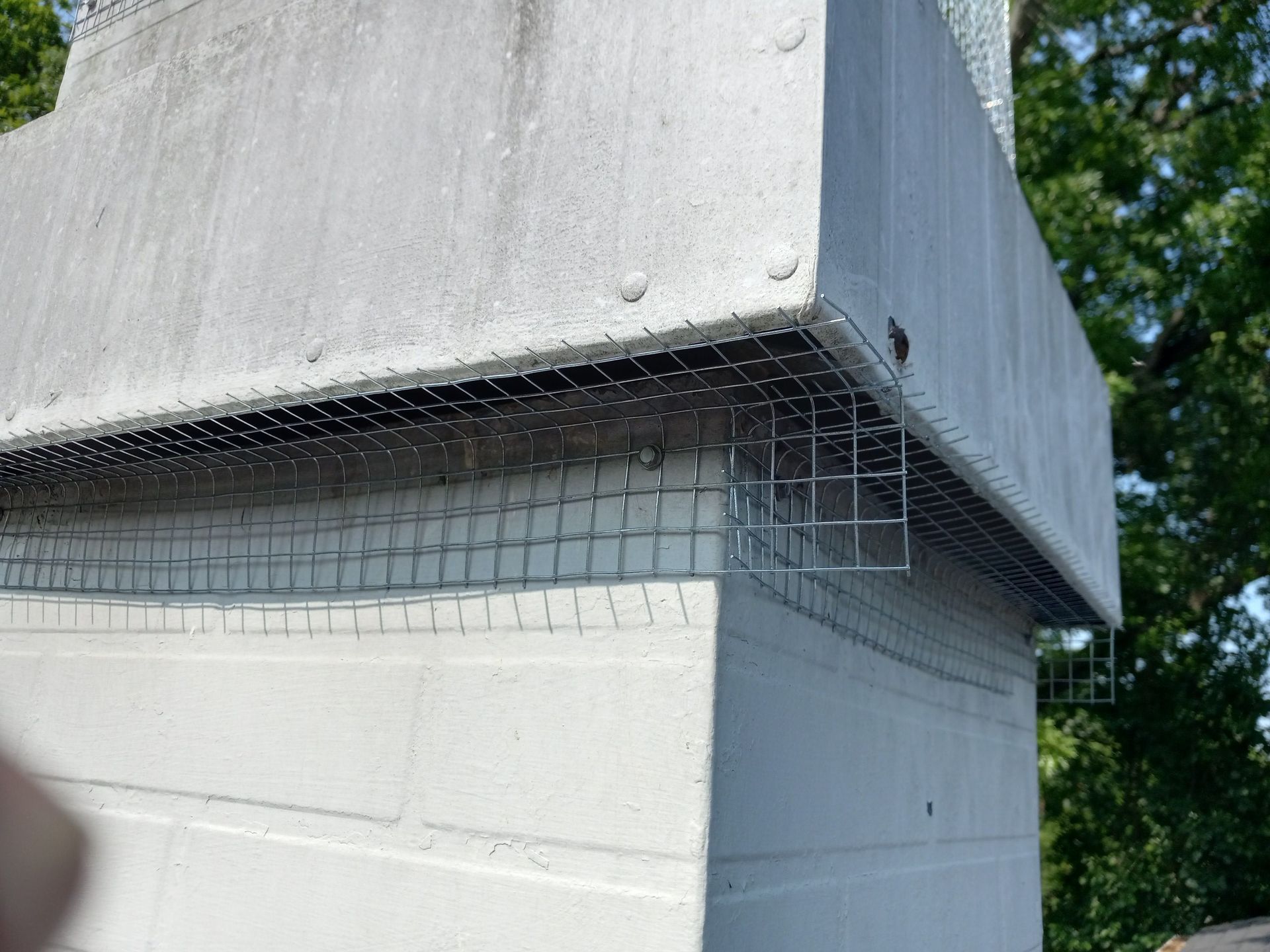 Concrete building corner with exposed wire mesh and white painted block wall outdoors