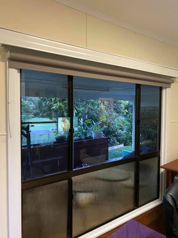 A Window With Tinted Glass And A Roller Blind — Mareeba Floor Covering Centre in Mareeba, QLD