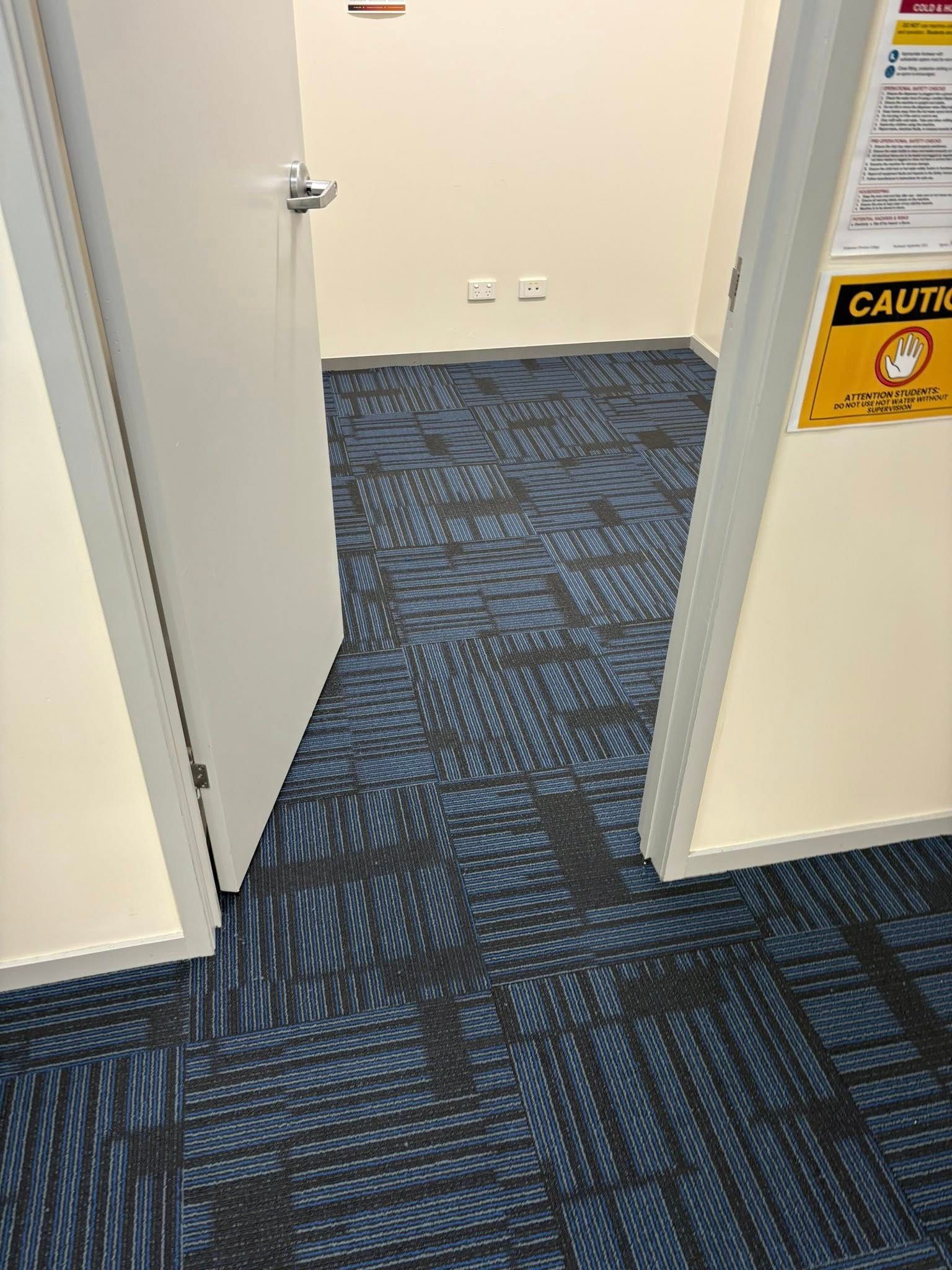 A Partially Open White Door Leading Into A Room With Blue Patterned Carpet — Mareeba Floor Covering Centre in Mareeba, QLD