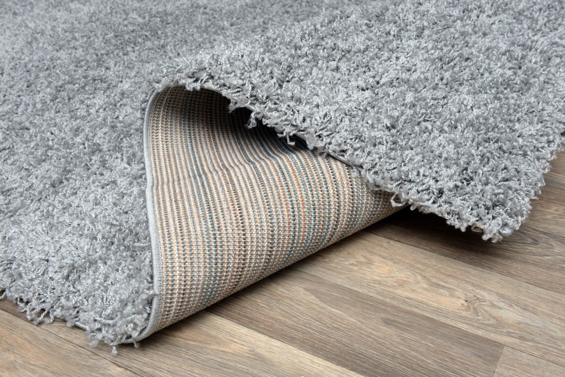 Gray Shaggy Rug, Partially Rolled Up, Revealing A Textured Backing — Mareeba Floor Covering Centre in Port Douglas, QLD