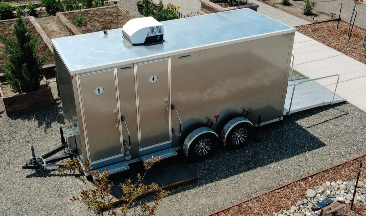 Silver enclosed cargo trailer parked on gravel in a yard, viewed from above