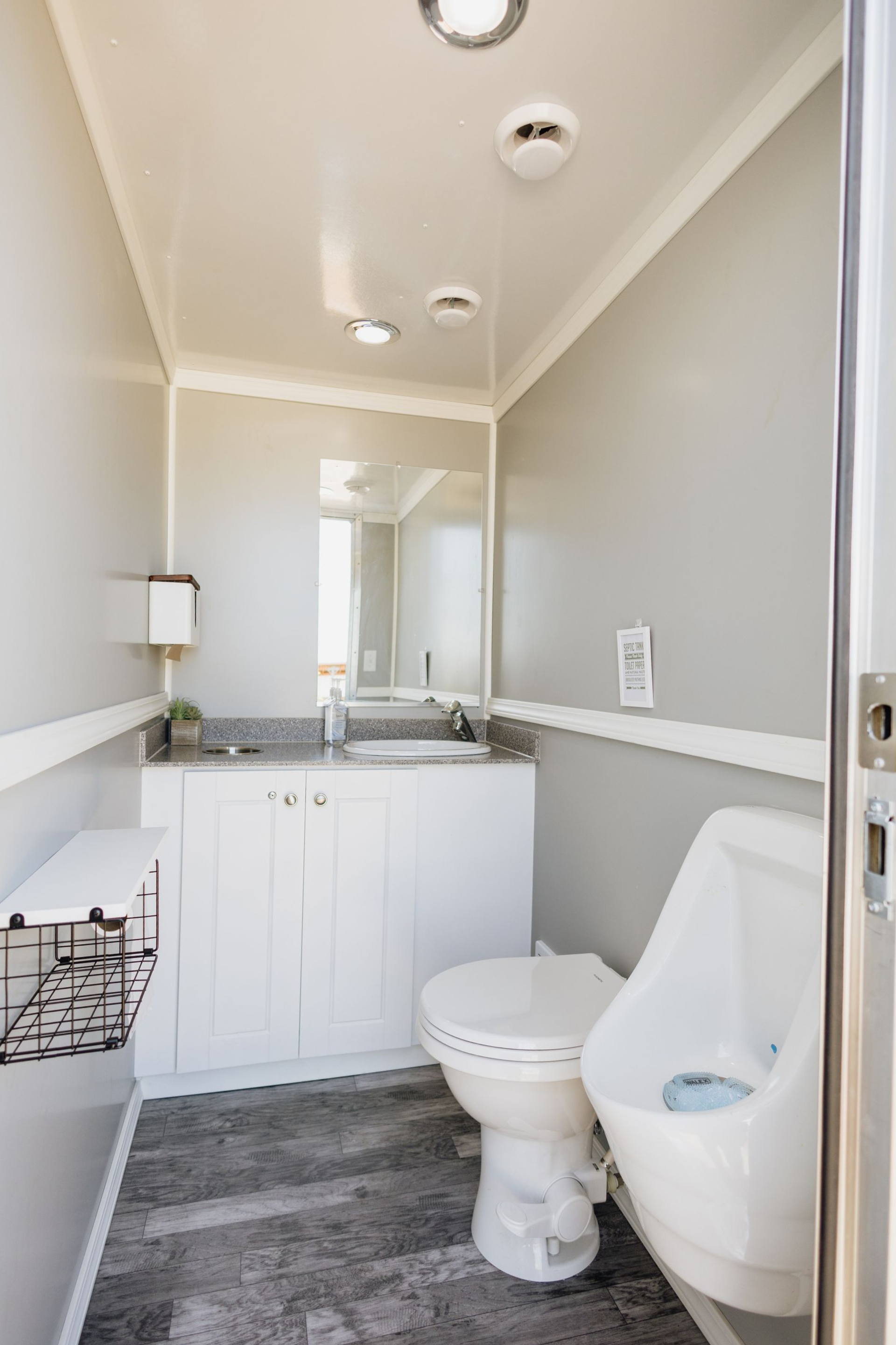 Small bathroom with white vanity, toilet, gray floor, and a shower-tub on the right.
