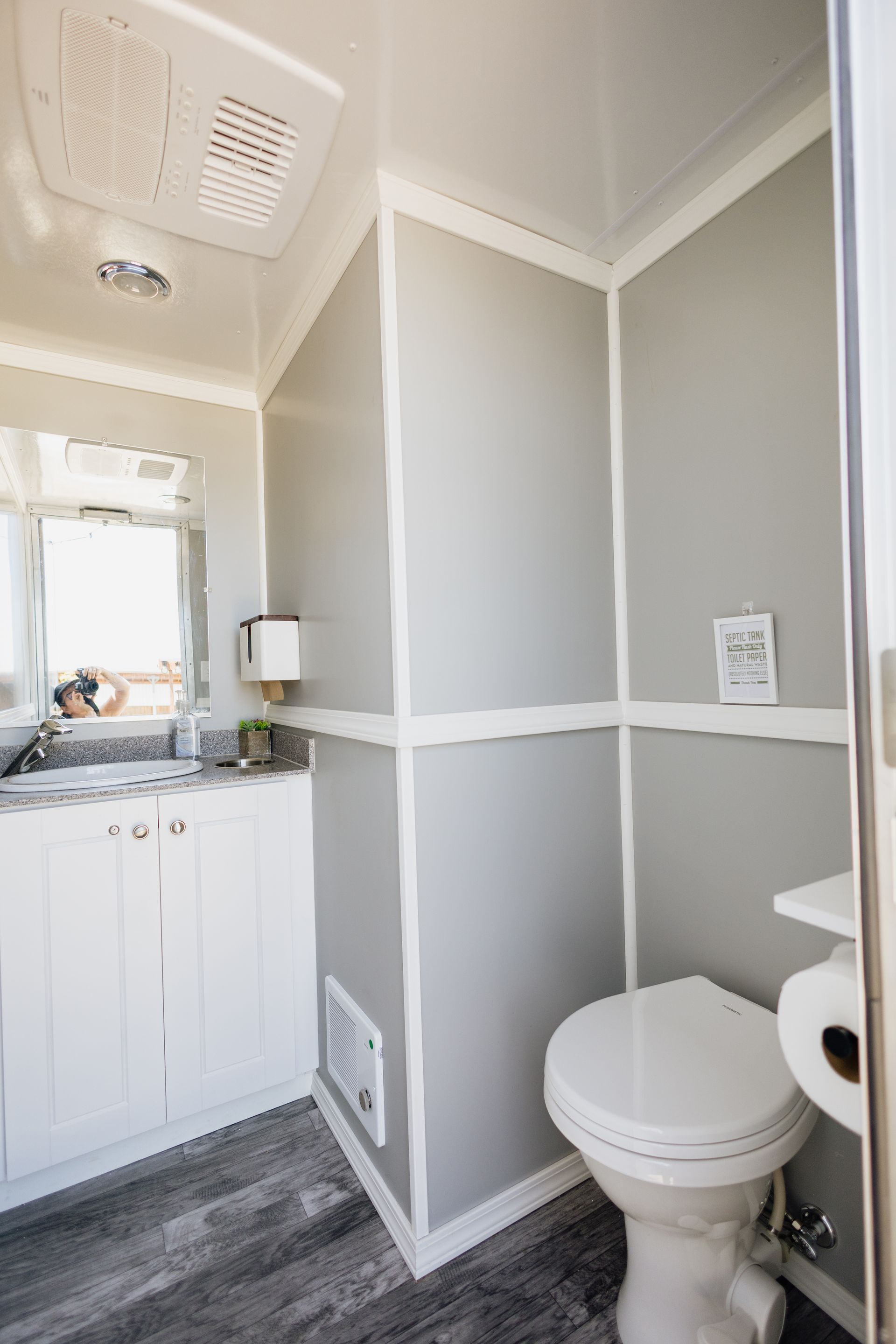 Small bathroom interior with gray walls, white trim, toilet, sink, and mirror cabinet.