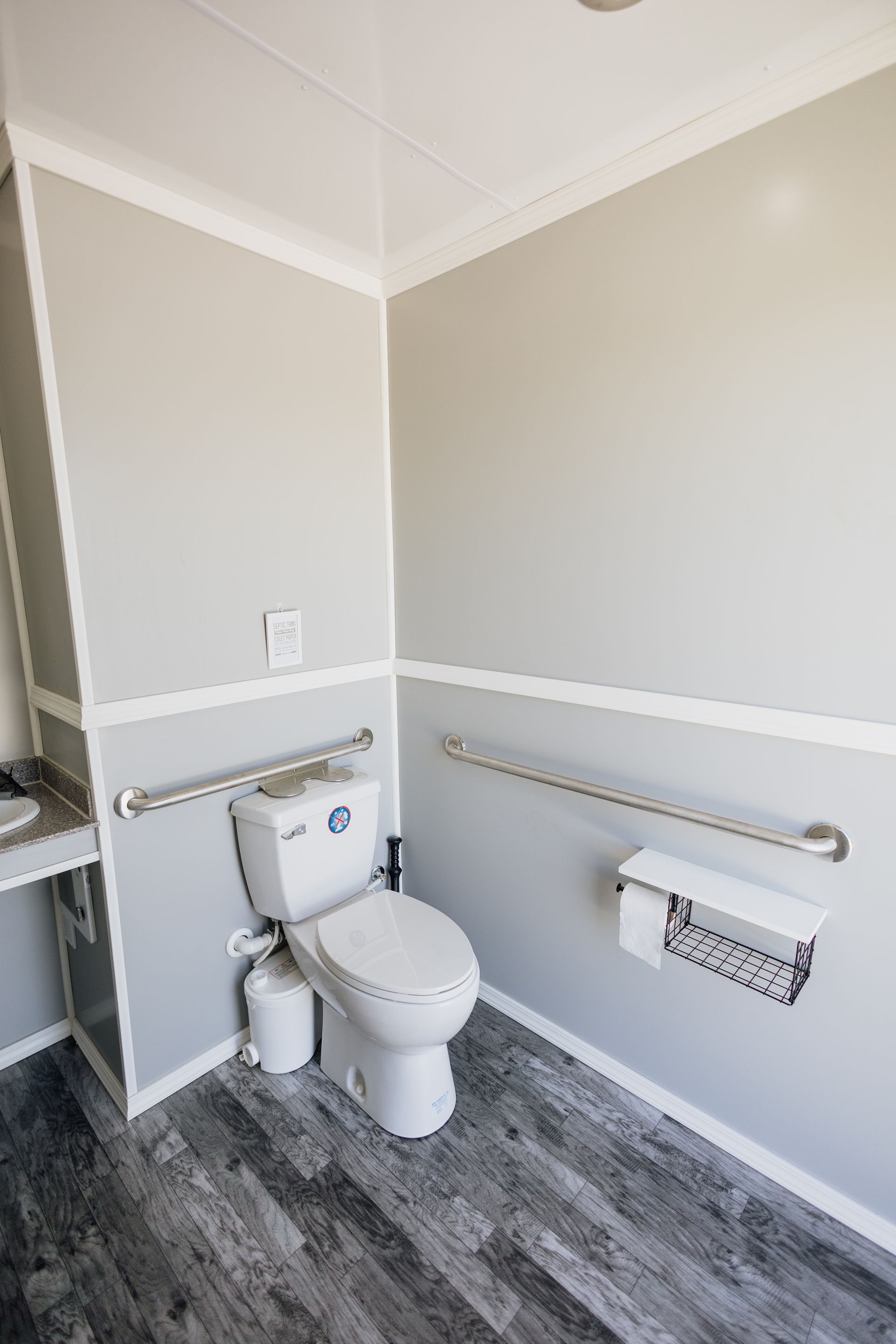 Accessible restroom with toilet, wall-mounted grab bars, and gray flooring