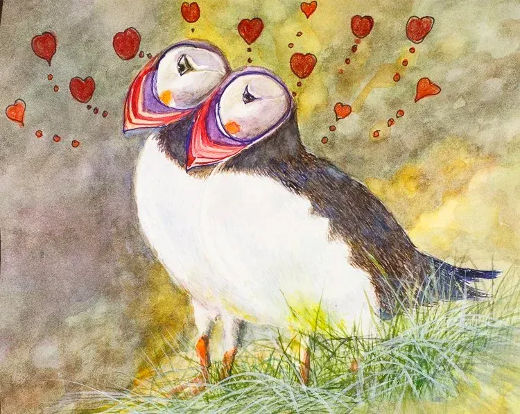 Two puffins with red hearts floating around them on a colorful grassy shore