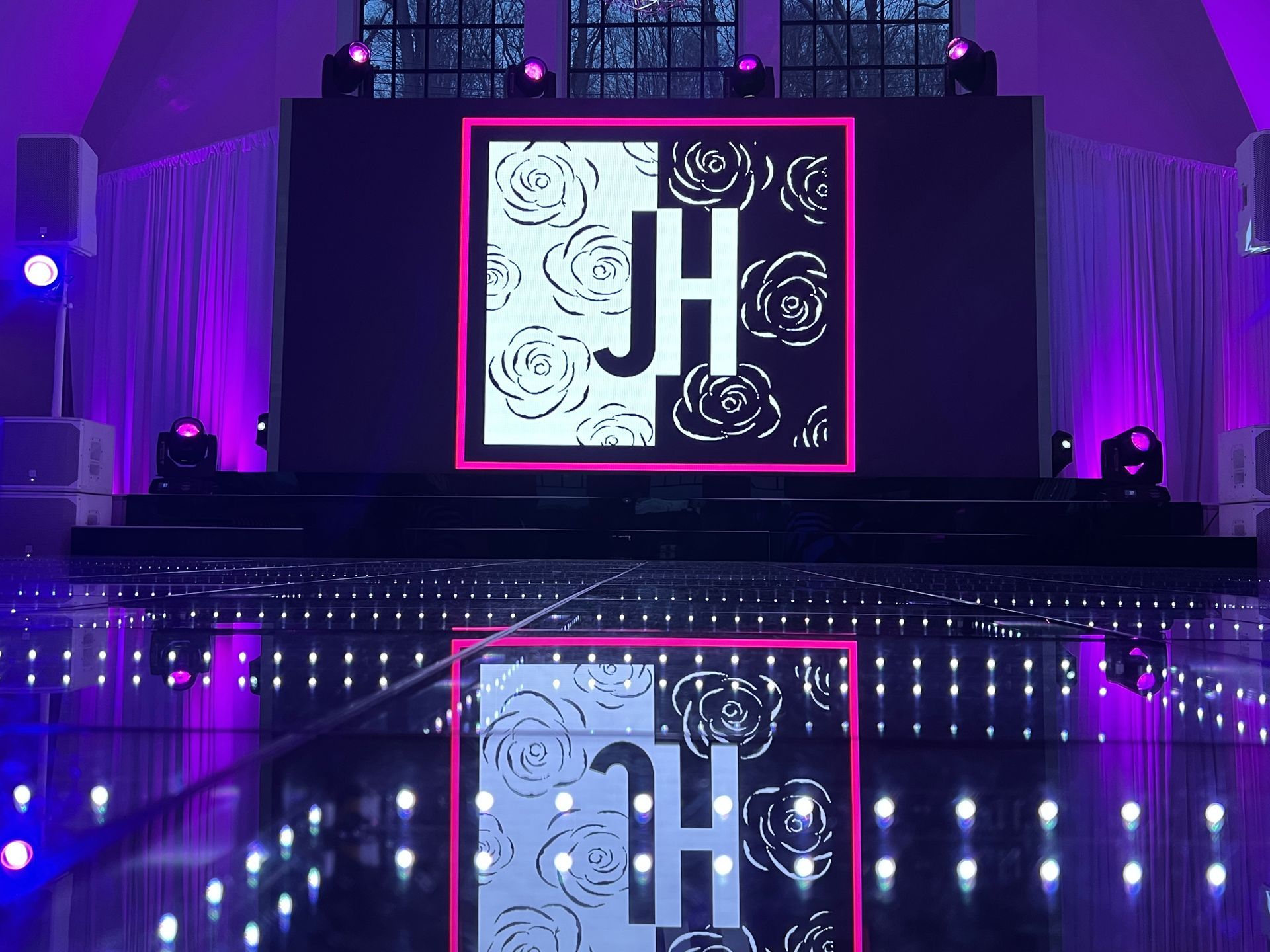 LED Video Wall and A large screen with a monogram on it is on a stage with purple lights.
