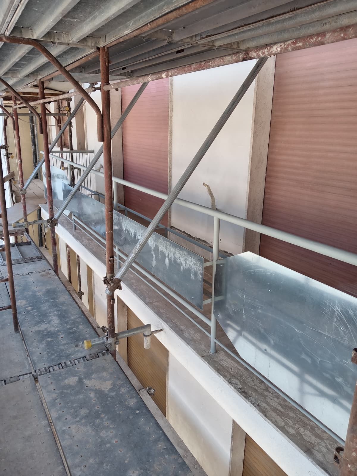 Ponteggi lungo la facciata esterna di un edificio con supporti metallici e passaggio pedonale chiuso in costruzione.