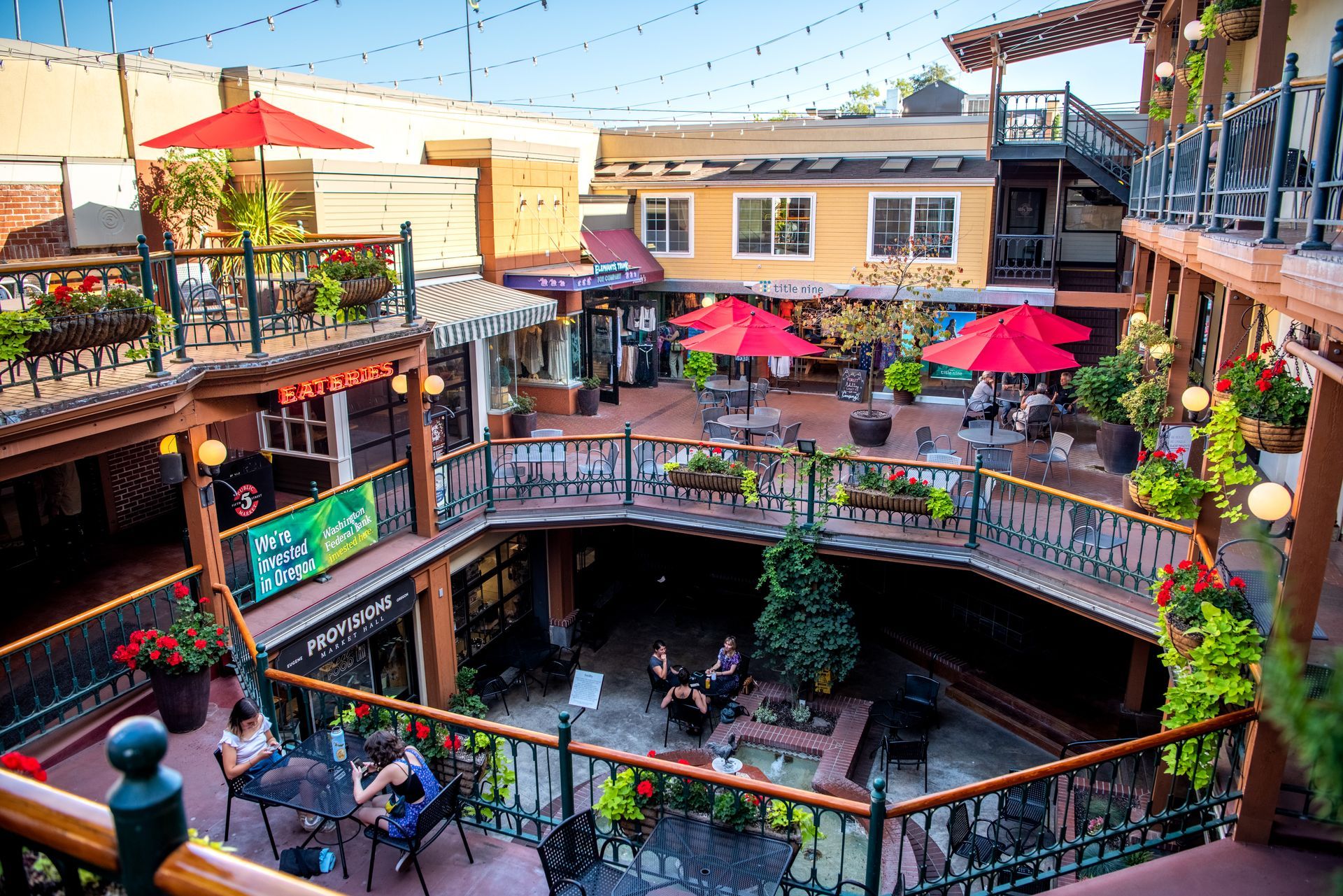 Patio of the Market Core with outdoor searing, red umbrellas, and people enjoying a blue skied summer day