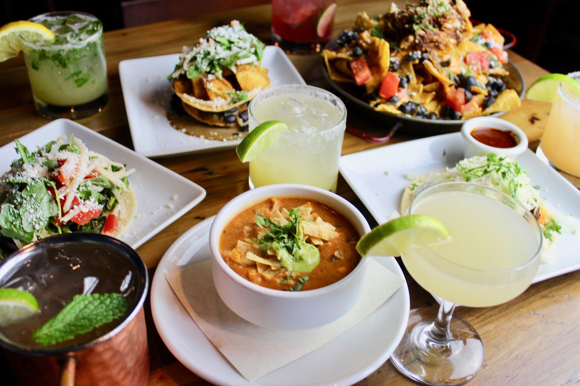 A delicious spread of Mexican-inspired dishes and cocktails at Carlita’s Rooftop at The Gordon Hotel, featuring colorful plates of nachos, salads, soup, and vibrant beverages with lime garnishes. Located in 5th Street Public Market, steps away from the Gordon Lofts.A delicious spread of Mexican-inspired dishes and cocktails at Carlita’s Rooftop at The Gordon Hotel, featuring colorful plates of nachos, salads, soup, and vibrant beverages with lime garnishes. Located in 5th Street Public Market, steps away from the Gordon Lofts.