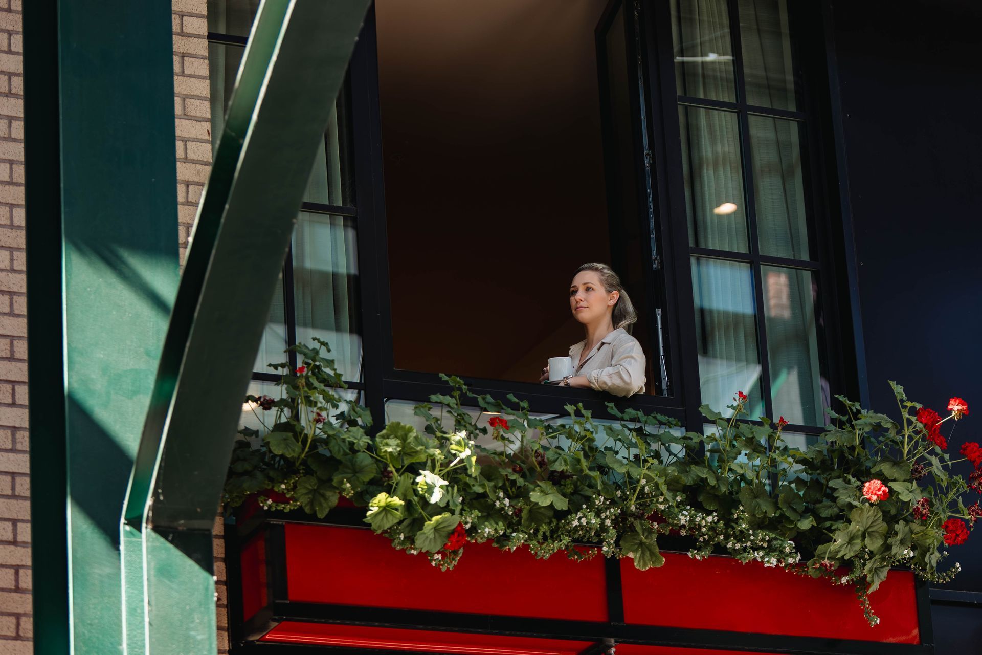 Woman looking out of a window with a cup of coffee in hand